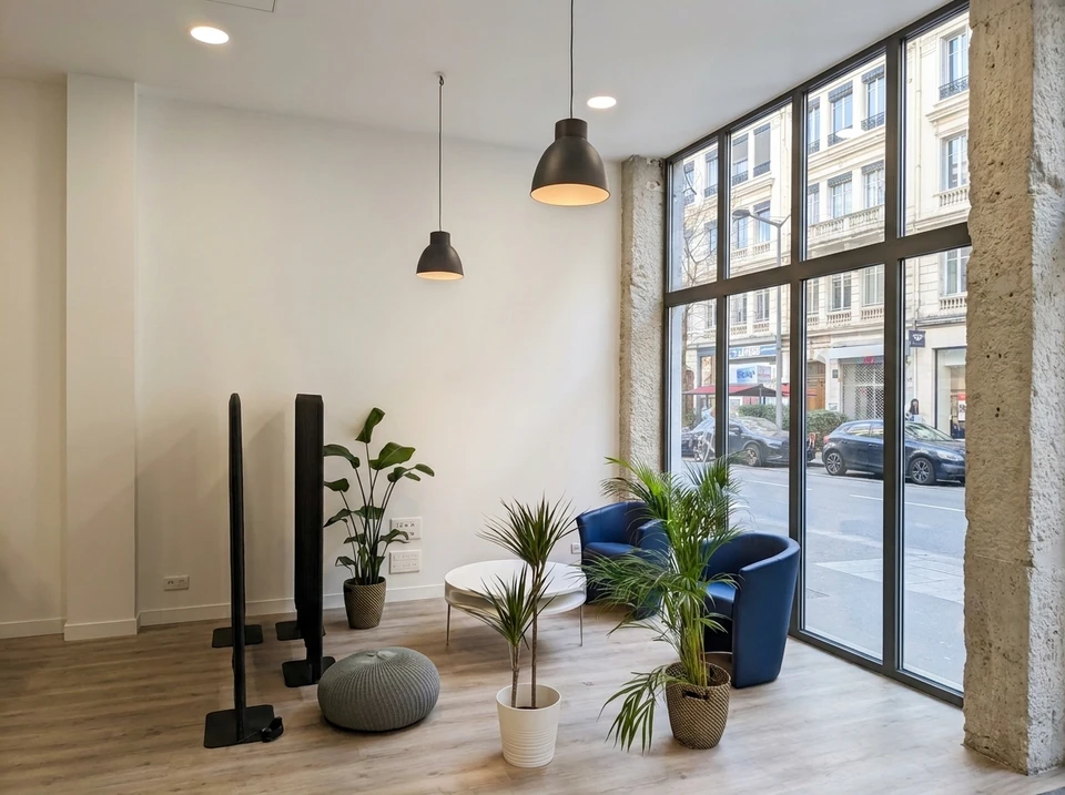 Espace de réception moderne avec coin salon : deux fauteuils barrel chair en velours bleu marine, table basse ronde blanche, plantes tropicales (strelitzia, dracaena, areca)